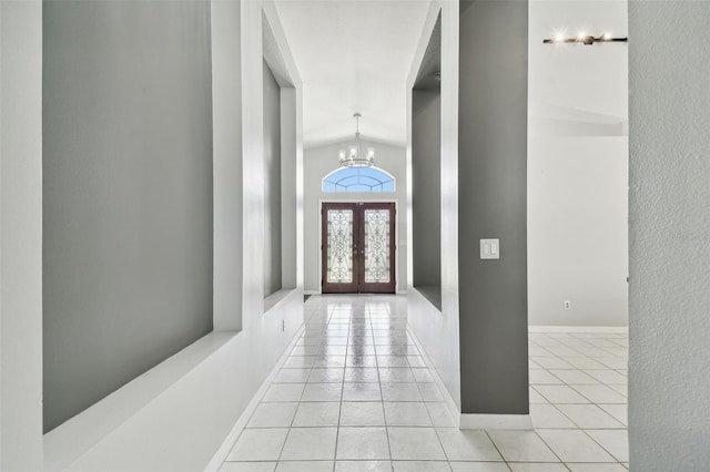 tiled foyer with lofted ceiling, a chandelier, and french doors