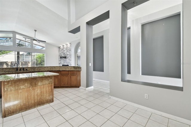 kitchen with dark stone countertops, vaulted ceiling, and light tile patterned flooring