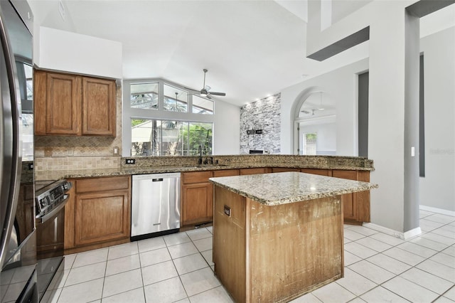 kitchen with sink, lofted ceiling, a kitchen island, stainless steel appliances, and ceiling fan