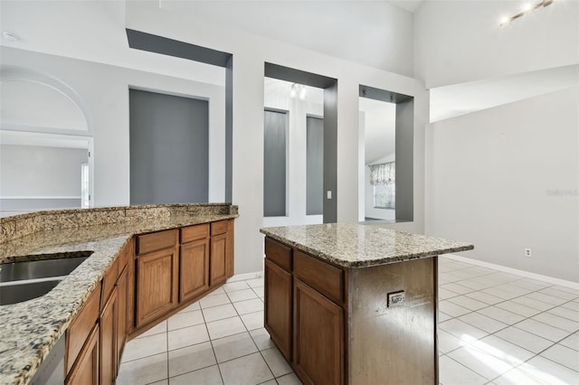 kitchen with sink, light stone countertops, light tile patterned floors, and a center island