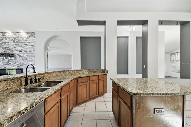 kitchen featuring light stone counters, light tile patterned floors, sink, a kitchen island, and stainless steel dishwasher