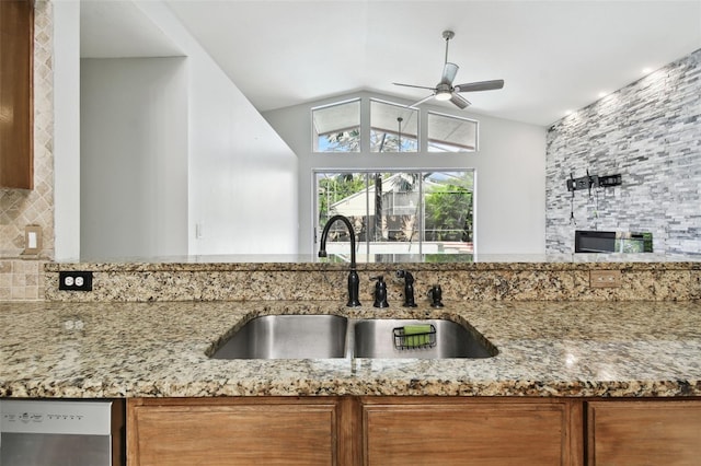 kitchen featuring ceiling fan, light stone countertops, sink, and tasteful backsplash