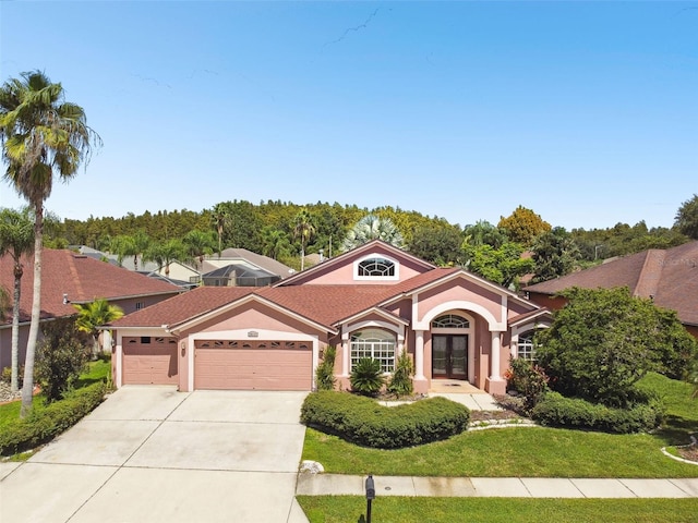 mediterranean / spanish-style house featuring a garage and a front lawn