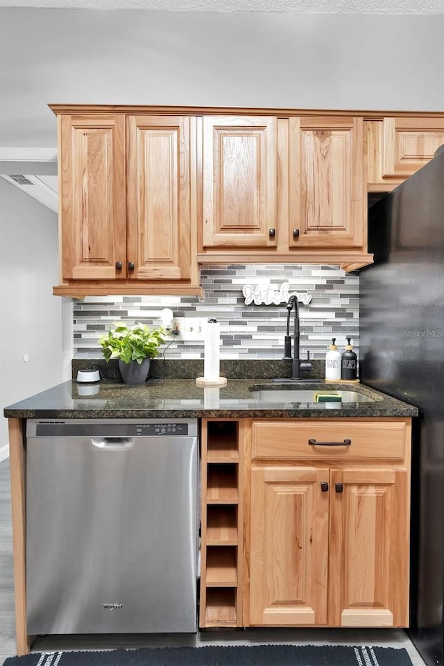 kitchen featuring sink, dishwasher, backsplash, black fridge, and dark stone counters