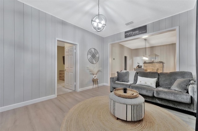 living room with wooden walls, hardwood / wood-style flooring, and a chandelier