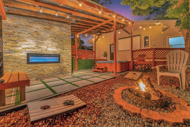 patio terrace at dusk featuring a fire pit and a pergola