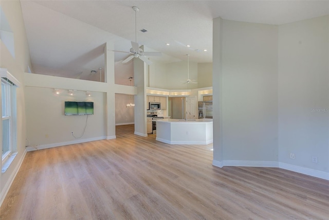 unfurnished living room featuring ceiling fan, light wood-type flooring, sink, and high vaulted ceiling