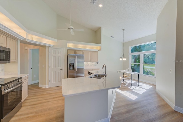 kitchen featuring high vaulted ceiling, a center island with sink, sink, decorative light fixtures, and stainless steel appliances