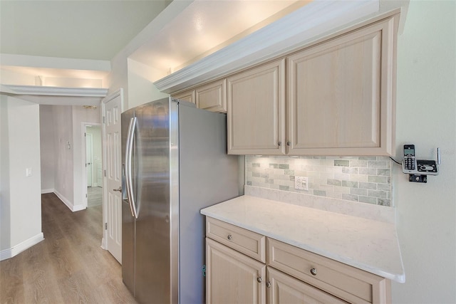 kitchen featuring decorative backsplash, stainless steel fridge, light brown cabinets, and light hardwood / wood-style floors