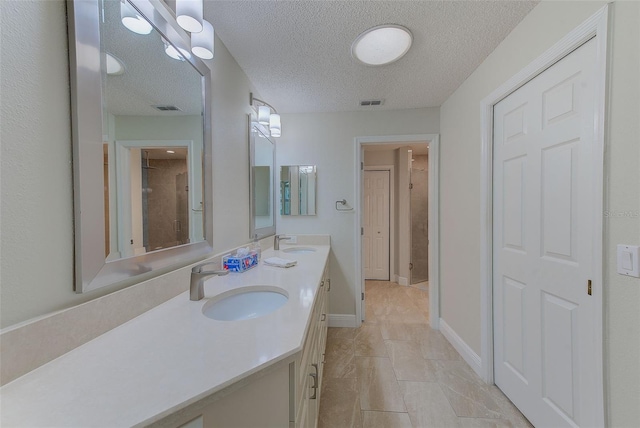 bathroom featuring vanity, a textured ceiling, a shower with shower door, and tile patterned flooring