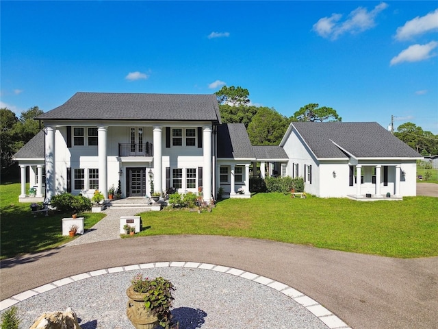 view of front of house with a balcony and a front yard