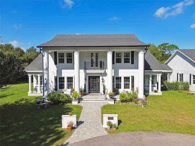 neoclassical home with a front yard and a balcony