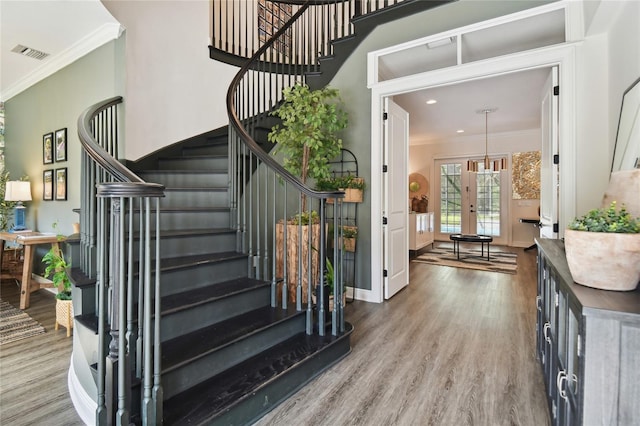 stairs featuring hardwood / wood-style floors and ornamental molding