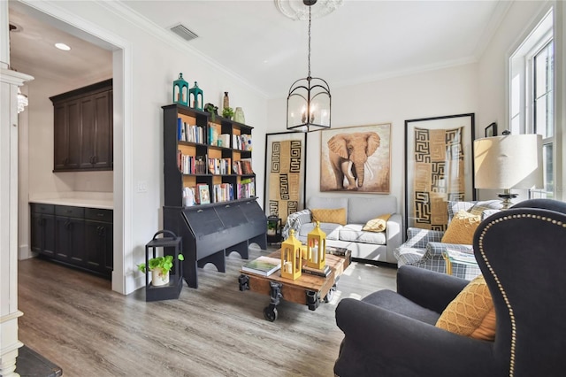 living area with light hardwood / wood-style floors, a chandelier, and crown molding