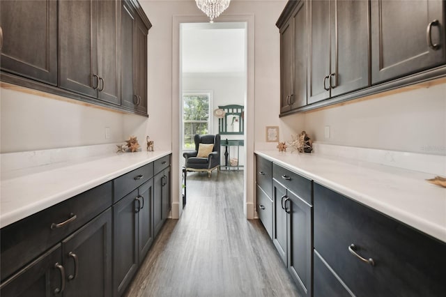 kitchen with light wood-type flooring, dark brown cabinets, and a notable chandelier