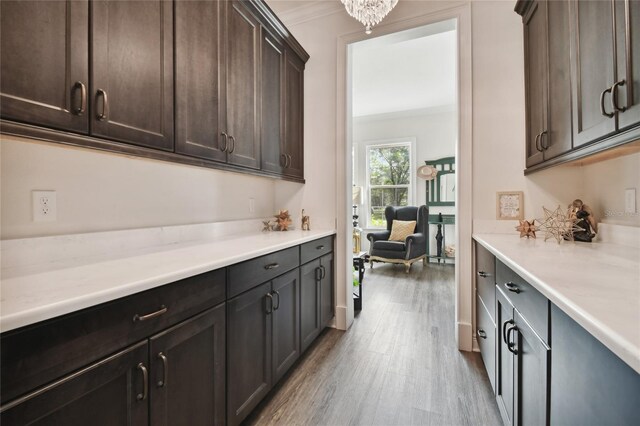 kitchen featuring ornamental molding, dark brown cabinets, light hardwood / wood-style floors, and a notable chandelier