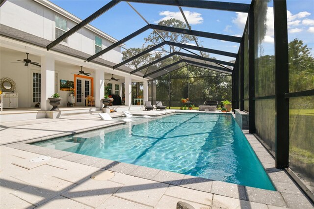 view of swimming pool with ceiling fan, a lanai, french doors, and a patio area