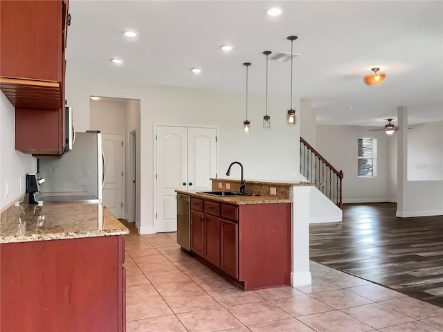 kitchen featuring ceiling fan, hanging light fixtures, sink, stainless steel dishwasher, and light wood-type flooring