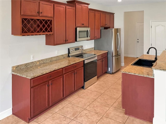 kitchen featuring light tile patterned flooring, sink, stainless steel appliances, and light stone counters