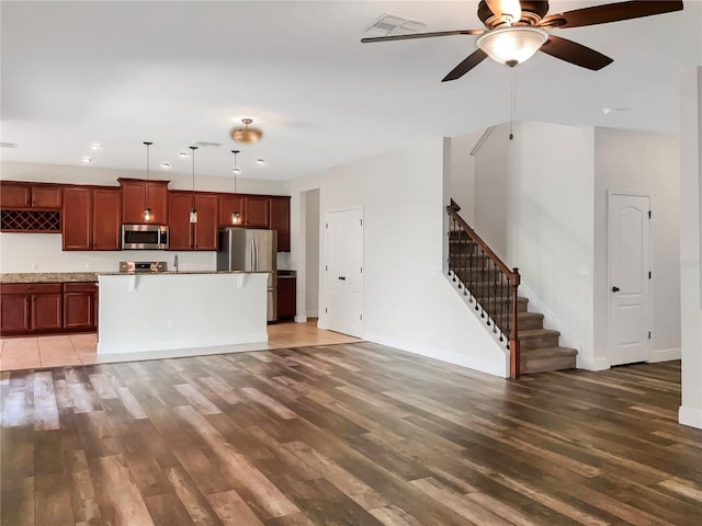 kitchen with appliances with stainless steel finishes, dark wood-type flooring, pendant lighting, and ceiling fan