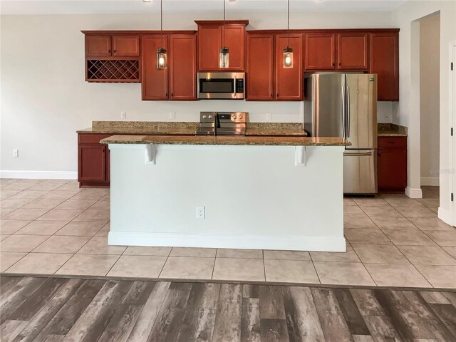 kitchen featuring pendant lighting, a breakfast bar area, appliances with stainless steel finishes, and a center island