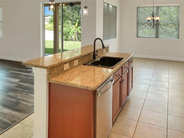 kitchen with pendant lighting, sink, a chandelier, dishwasher, and light stone countertops