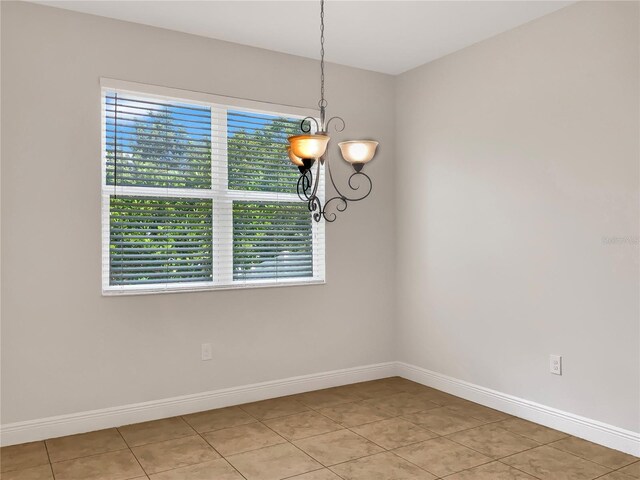 empty room featuring an inviting chandelier and light tile patterned floors