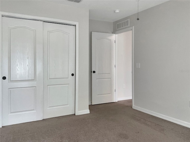 unfurnished bedroom featuring a closet and dark colored carpet