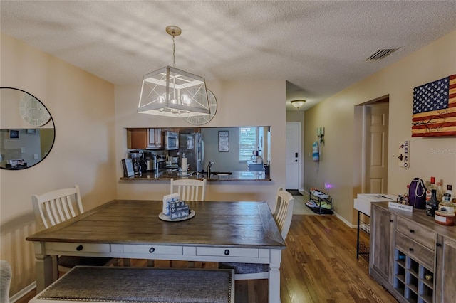 dining space with a chandelier, hardwood / wood-style floors, a textured ceiling, and sink