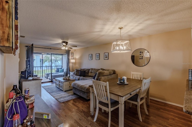 dining space featuring a textured ceiling, ceiling fan with notable chandelier, and dark wood-type flooring