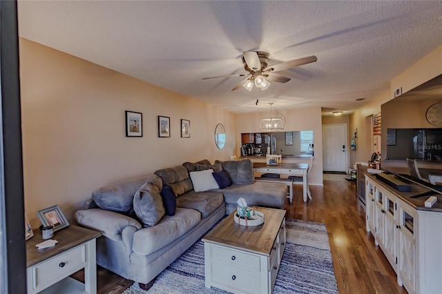 living room with a textured ceiling, ceiling fan with notable chandelier, and dark hardwood / wood-style floors