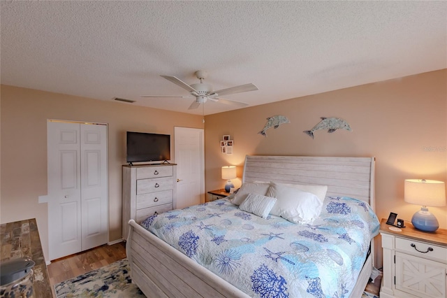 bedroom with wood-type flooring, a textured ceiling, a closet, and ceiling fan