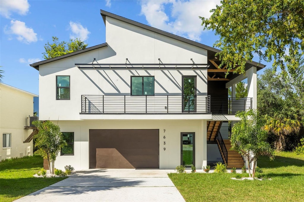 contemporary home with a balcony, a front lawn, and a garage