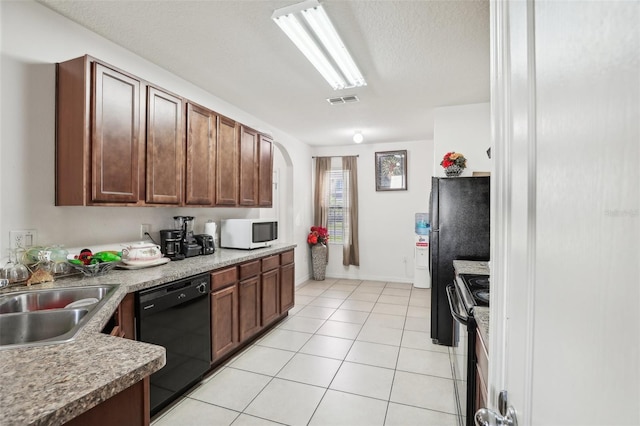 kitchen featuring black dishwasher, a textured ceiling, sink, stainless steel range with electric cooktop, and light tile patterned floors