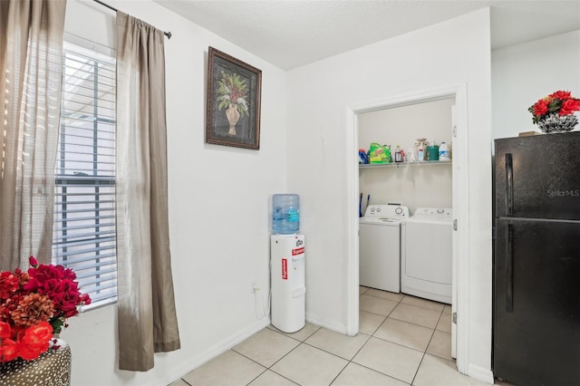 washroom featuring water heater, light tile patterned flooring, and washing machine and dryer