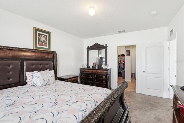 bedroom with a spacious closet and light carpet