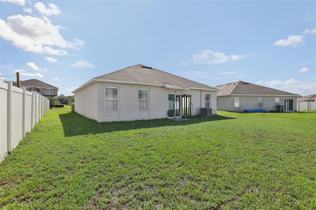 rear view of house featuring a lawn and central AC unit