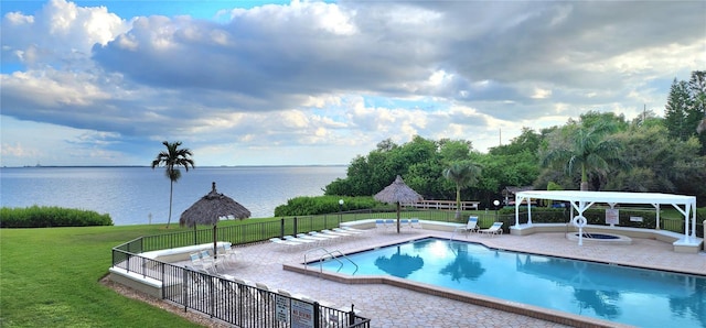 view of pool with a patio, a water view, and a lawn