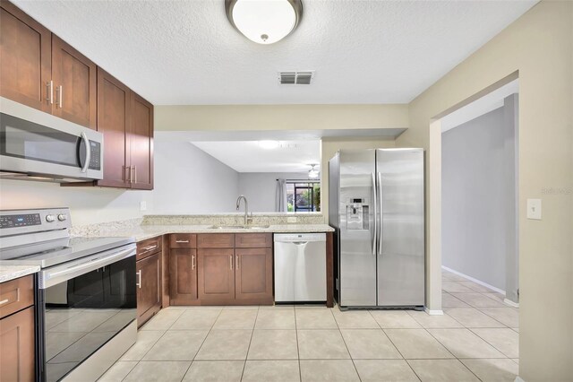 kitchen featuring a textured ceiling, stainless steel appliances, sink, and light tile patterned flooring