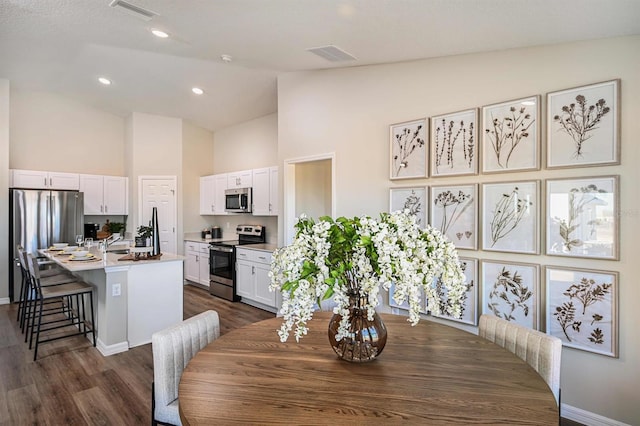 dining space featuring dark hardwood / wood-style flooring and high vaulted ceiling