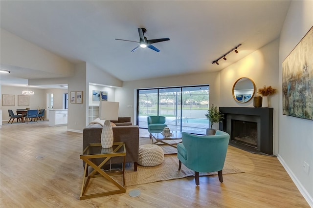 living room featuring ceiling fan, track lighting, lofted ceiling, and light hardwood / wood-style floors