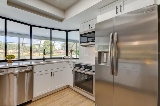 kitchen featuring stainless steel appliances, light wood-type flooring, sink, and white cabinetry