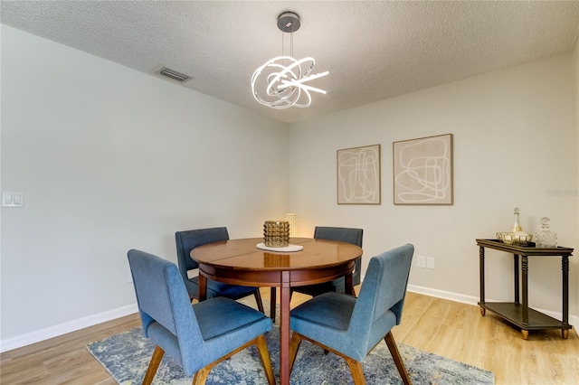 dining space featuring a notable chandelier, a textured ceiling, and hardwood / wood-style flooring