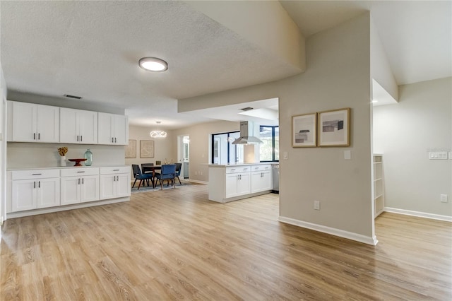 unfurnished living room with a textured ceiling, lofted ceiling, and light hardwood / wood-style floors