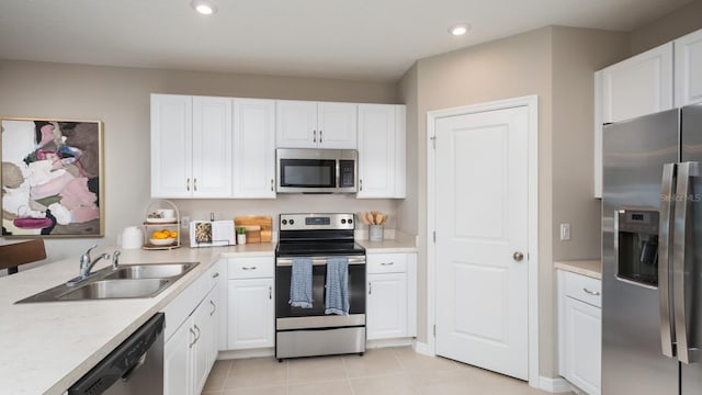 kitchen with light tile patterned floors, white cabinets, stainless steel appliances, and sink