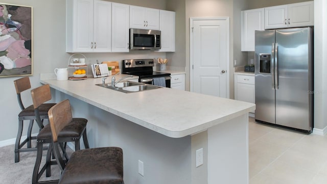 kitchen featuring appliances with stainless steel finishes, kitchen peninsula, sink, and a breakfast bar