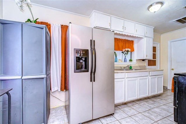 kitchen featuring sink, white cabinets, light tile patterned floors, crown molding, and stainless steel fridge