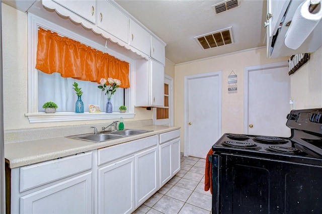 kitchen featuring light tile patterned floors, sink, electric range, and white cabinets