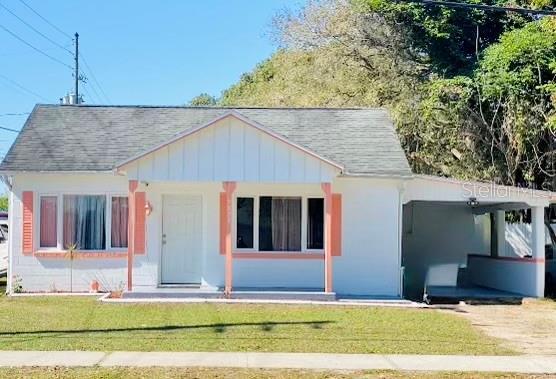 view of front of house with board and batten siding, a front yard, and roof with shingles