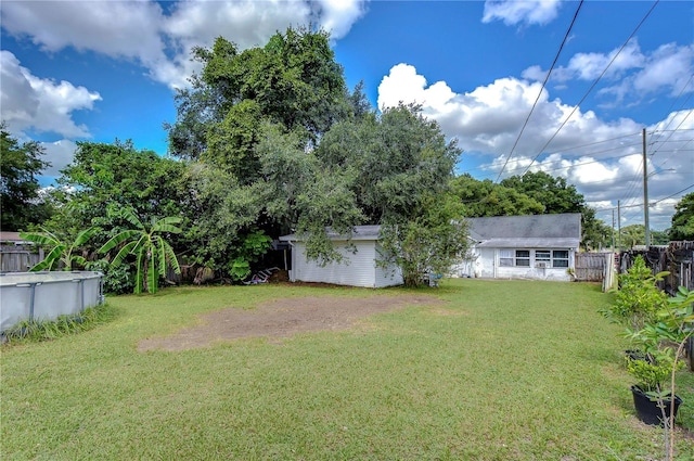 view of yard with driveway, fence, and an outdoor pool